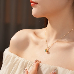 Close-up of a gold-plated necklace with a blue cat-eye stone pendant on a female model