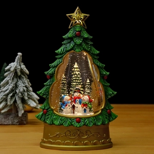 Close-up of glowing Christmas tree snow globe with snowman and warm festive lights