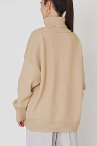 Détail d'un pull à col roulé ample en maille avec poignets et ourlet côtelés beige