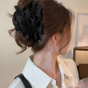 Elegant oversized black fabric flower hair scrunchie shown on model's hairstyle