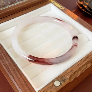 Detail of round agate bangle with ink-red patterns in a velvet walnut jewelry box