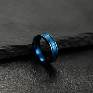 Minimalist blue stainless steel ring with Roman numeral engravings on a rock surface