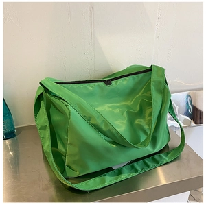 Detail view of large green oxford sports bag with black zipper on metal surface