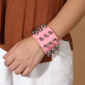 Close-up of pink leather punk bracelet featuring three rows of silver cone studs on a wrist
