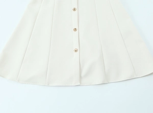 Detailed close-up of cream mini dress showing button closure and fabric texture