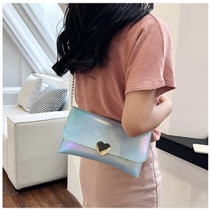 Holographic light blue mini purse with golden heart clasp shown on a model in a home setting