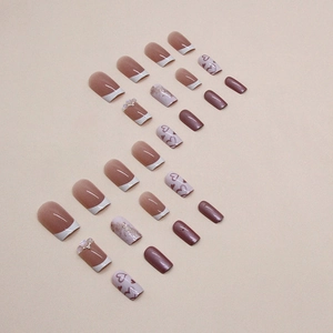 White French press-on nails with heart patterns, aurora finish, and pearl embellishments