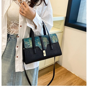 Detail of crocodile texture flap on women's handbag with gradient teal scales and lock