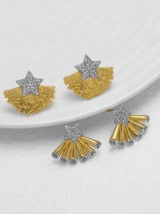 Macro detail of gold fan-shaped earrings with star-shaped zircon pavé on white surface
