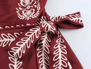 Detail of red resort dress showing white leaf pattern fabric and tied bow knot closeup