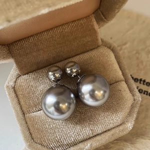 Close-up of grey pearl double-bead earrings in a beige velvet jewelry display box