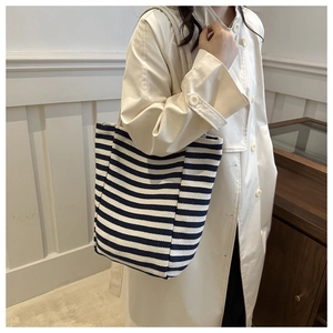 Side view of large striped canvas tote bag worn by model for daily commute and shopping
