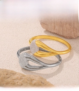 Detail of PVD electroplated gold and silver bracelets with pavé diamonds on wood