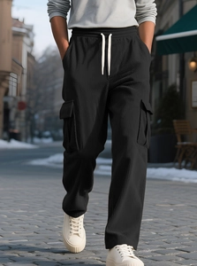 Detailed outdoor shot of black corduroy cargo jogger pants with white drawstring waist