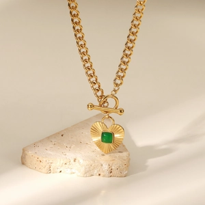 Macro view of gold heart pendant with green agate stone and toggle clasp detail