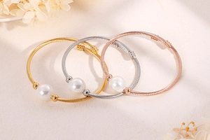 Trois bracelets torsadés en or, argent et rose doré avec perles sur fond textile