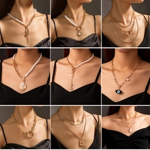 Close-up of gold chain necklaces with pearls and charms in a layered style on model