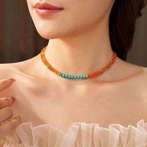 Detail of double-layer beaded necklace with orange and blue faceted stones and gold spacers