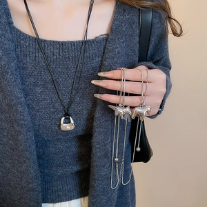 Close-up of brushed metal horse pendants and silver tassels on long necklaces