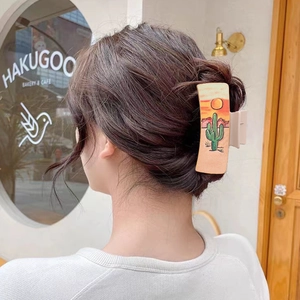Matte beige hair claw clip with cactus desert print worn by model in casual cafe setting