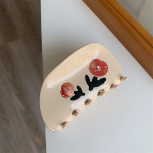 Detailed view of beige tulip hair claw clip with red floral patterns and gold accents