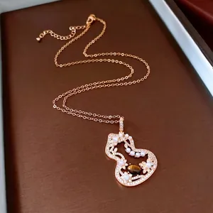 Tiger eye stone and pearl gourd pendant necklace in rose gold on a leather tray