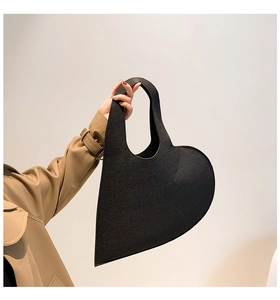 Close-up of black heart-shaped felt handbag with structured texture for chic styling