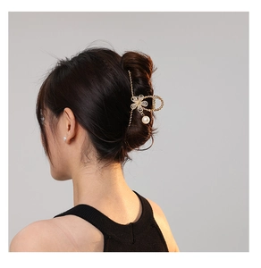 Detail shot of a metal flower hair claw with rhinestone accents and pearl pendant