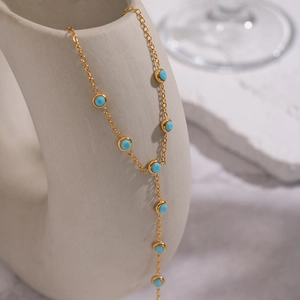 Elegant 18K gold plated stainless steel Y-necklace with turquoise beads on ceramic stand
