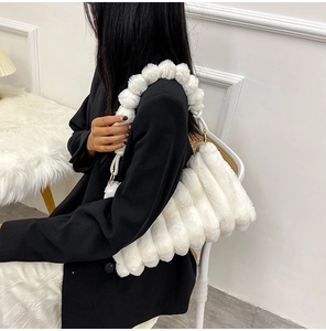 Detail of white plush handbag featuring unique faux fur ball chain design and gold hardware