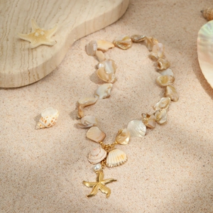 Marine beach necklace with sea shells, gold starfish charms and white pearls on sand