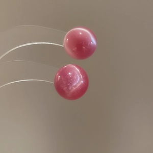 Macro shot of pink cat-eye stone round earrings featuring a glossy polished finish