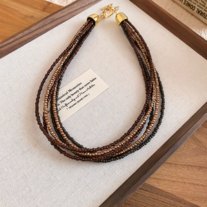 Detailed macro view of multi-layer beaded necklace with vintage brown beads and gold clasp