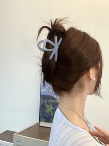 Detail of elegant dusty blue bow hair claw clip styled on a woman's half-up hair