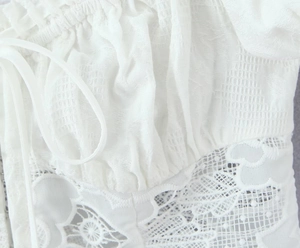 Vue macro d'une délicate broderie en dentelle blanche et d'un tissu plissé sur cet ensemble