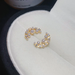 Macro shot of gold-plated crescent moon earrings with white pearls and zircons