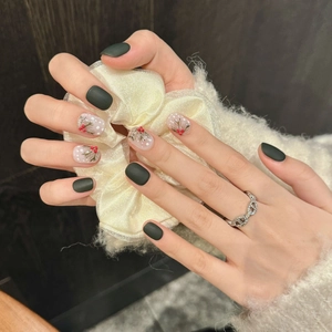 Faux ongles faits main motif hiver avec houx et baies sur fond vert foncé mat