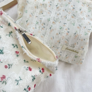 Détail de trousse à maquillage fleurie en dentelle avec fermeture éclair en métal