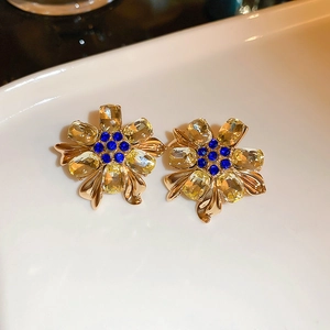 Macro view of vintage gold flower earrings with amber crystals and blue rhinestones