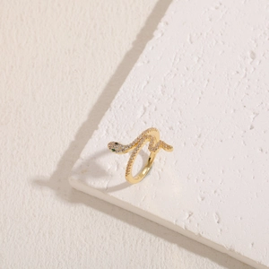 Detail of gold snake ring with white cubic zirconia and green gemstone eye accents