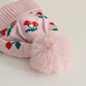 Pink winter knit hat for toddlers with cherry pattern and large fluffy pom-pom