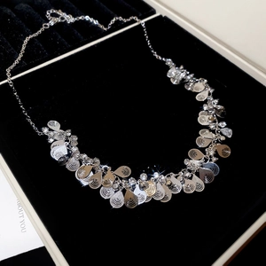 Close-up of teardrop tassels and crystal inlays on a necklace in a velvet jewelry box