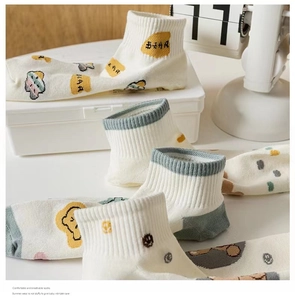 Detail showing white breathable cotton bear socks in a cozy storage box setting