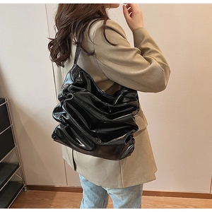 Dettaglio di borsa a spalla in pelle verniciata nera lucida con design a pieghe vintage