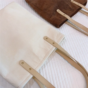 Close-up of corduroy tote bags with reinforced PU handles and gold rivet details