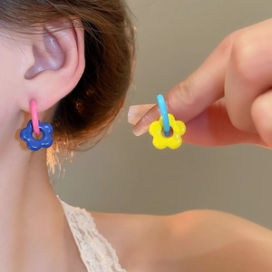 Macro detail of colorful floral hoop earrings featuring vibrant enamel flower charms