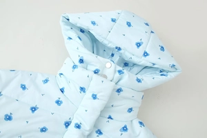 Detail of light blue floral puffer jacket hood with snap buttons and premium stitching