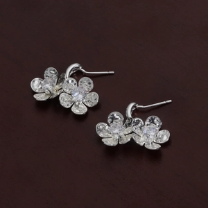 Close-up of silver floral stud earrings featuring hammered petals and sparkling cubic zirconia