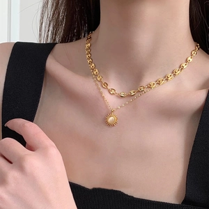 Close-up of double-layered gold necklace with pig-nose chain and sunflower pendant