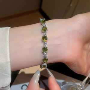 Sparkling zircon geometric bracelet with green gemstones shown on a female wrist